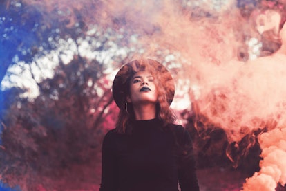Young woman surrounded by a cloud of smoke, feeling empowered by the March 21, 2022 weekly horoscope...