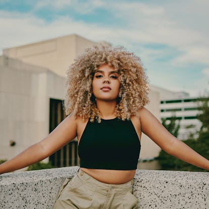 Young woman with big curly blonde hair, feeling empowered by the March 21, 2022 weekly horoscope for...
