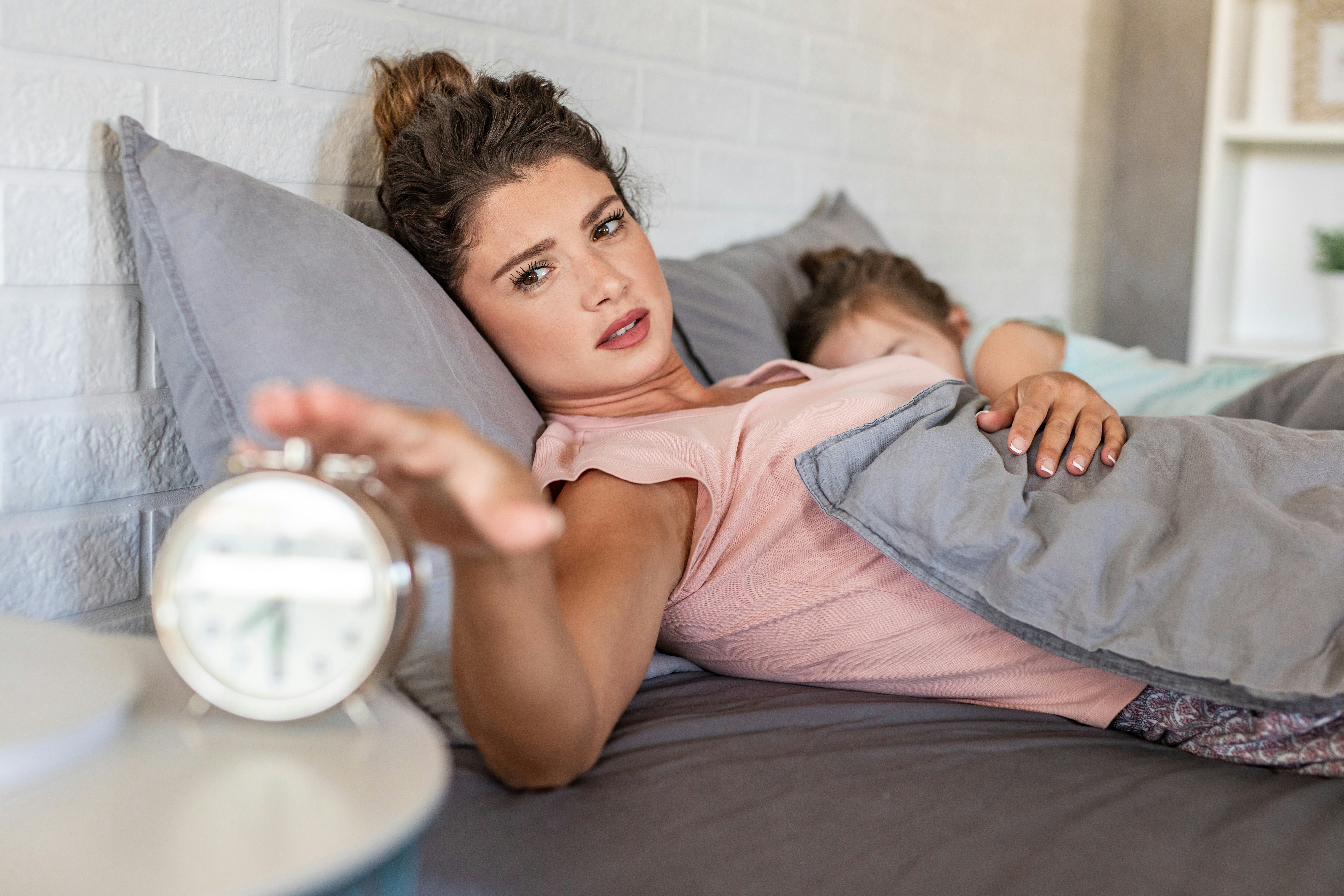 Woman sleeping with her daughter and waking up with alarm