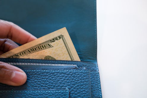 woman holding wallet with $20 u.s. paper bill showing