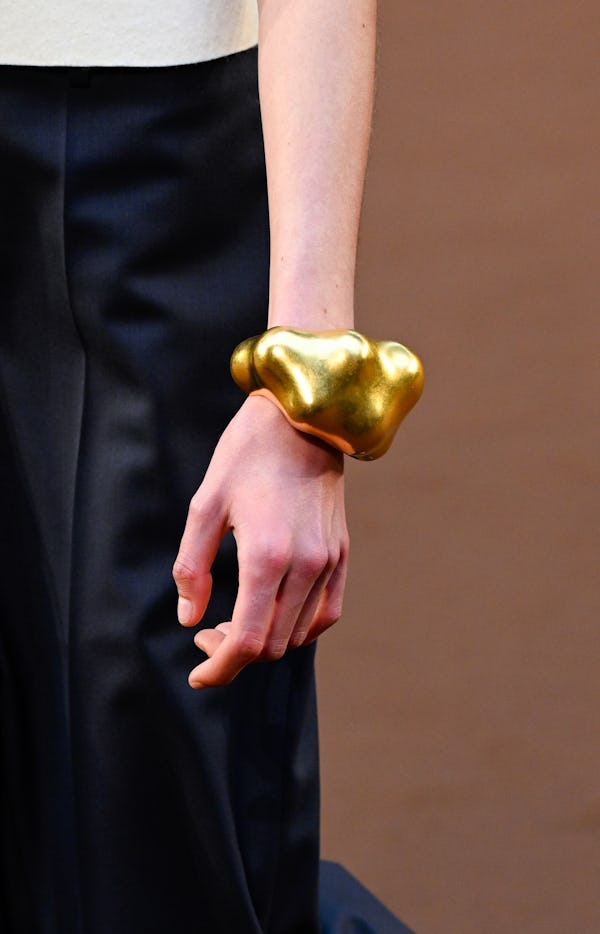 a model wearing a sculptural gold bangle bracelet on the Loewe runway
