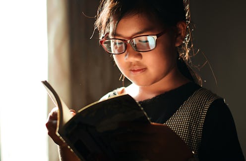 young girl with glasses reading a book