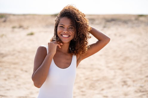 Shot of a young african american smiling woman spending the day at the beach in summer