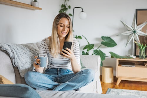 Young woman using Twitter Shops on her couch at home.