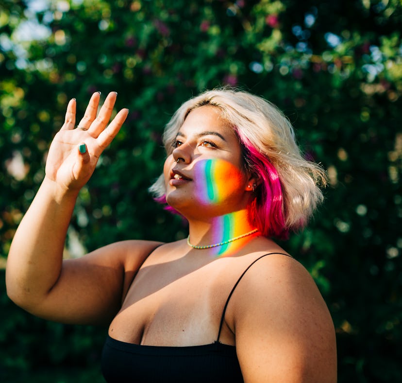young woman shields her face from the sun as a rainbow shadow is cast across her face