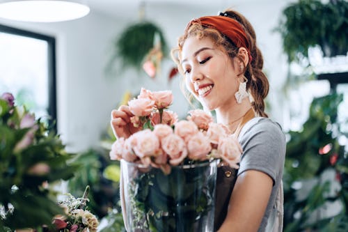 A woman arranges pink roses in a vase. Here's your daily horoscope for March 15, 2022.