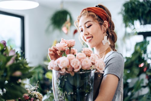 A woman arranges pink roses in a vase. Here’s your daily horoscope for March 15, 2022.