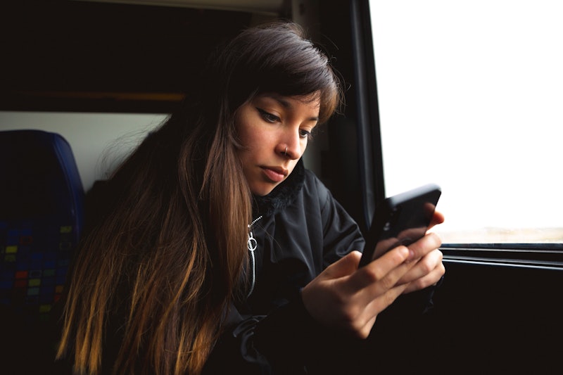 Young woman using smartphone on train