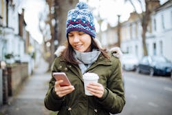 A woman reads tweets in order from most recent to oldest on her phone while drinking coffee.