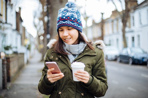A woman reads tweets in order from most recent to oldest on her phone while drinking coffee.