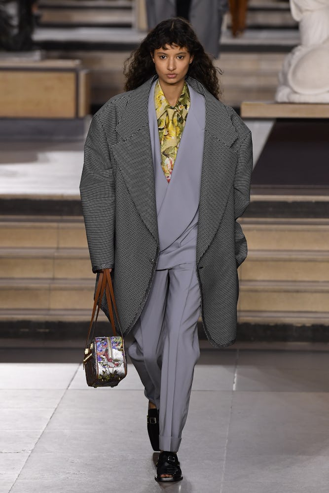 a model wearing an oversize grey coat and suit on the Louis Vuitton runway