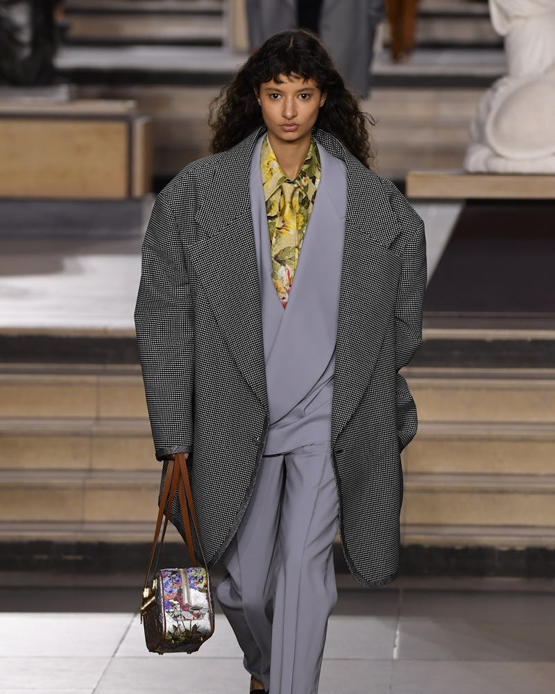 a model wearing an oversize grey coat and suit on the Louis Vuitton runway
