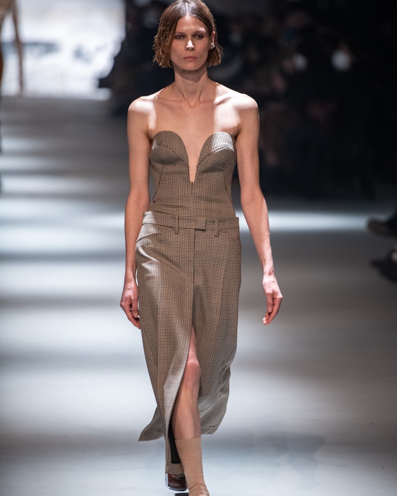 a model wearing a brown plaid bustier top and pencil skirt on the N°21 runway