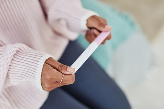 Cropped shot of an unrecognizable woman sitting on her bed alone and waiting for a pregnancy test re...