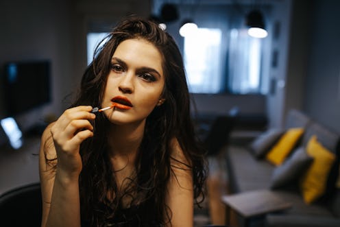 Attractive young woman applying lipstick at home