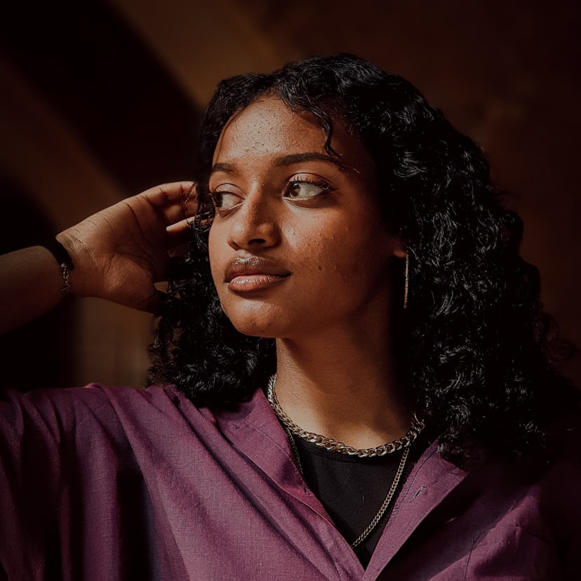 young woman tucks hair behind ear as she reflects on pluto retrograde 2022