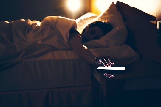 Morning shot of a sleepy person lying in bed, reaching out to the phone to turn off the alarm, wakin...