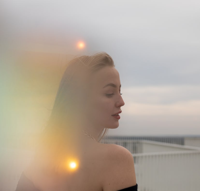 Young woman surrounded by orbs of light, embracing the March 21, 2022 weekly horoscope for her zodia...