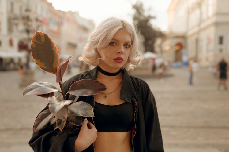 Young woman holding onto a plant, embracing the March 21, 2022 weekly horoscope for her zodiac sign.