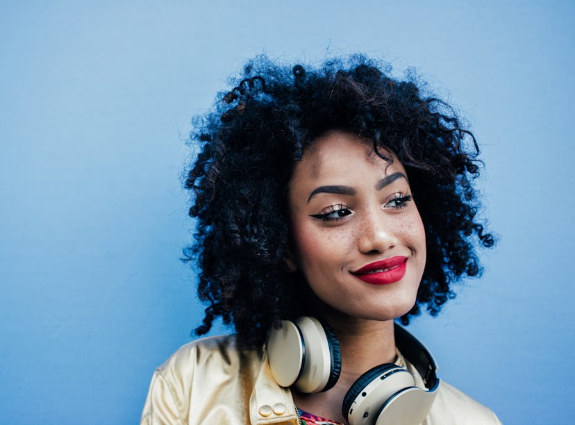 Young woman wearing headphones, knowing her zodiac sign will have the best week of March 28, 2022.