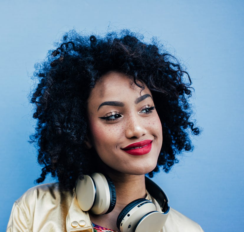 Young woman wearing headphones, knowing her zodiac sign will have the best week of March 28, 2022.