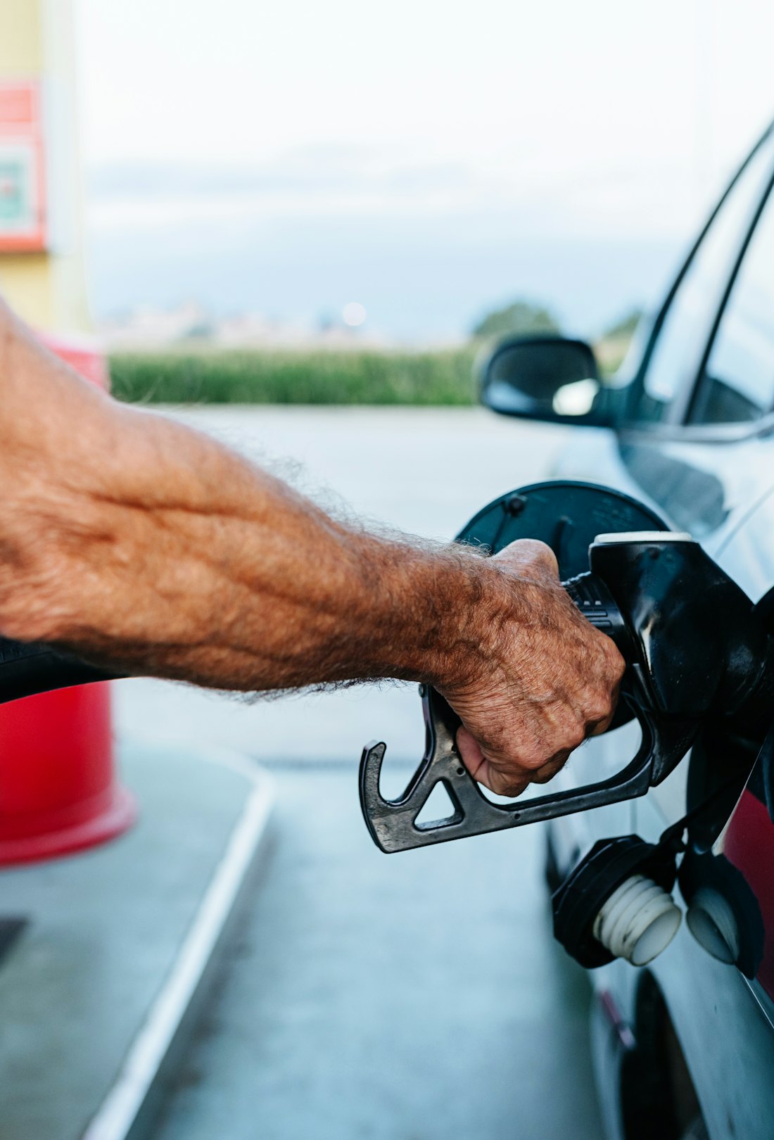 Close up view of a senior man filling the tank of his car at the gas station.