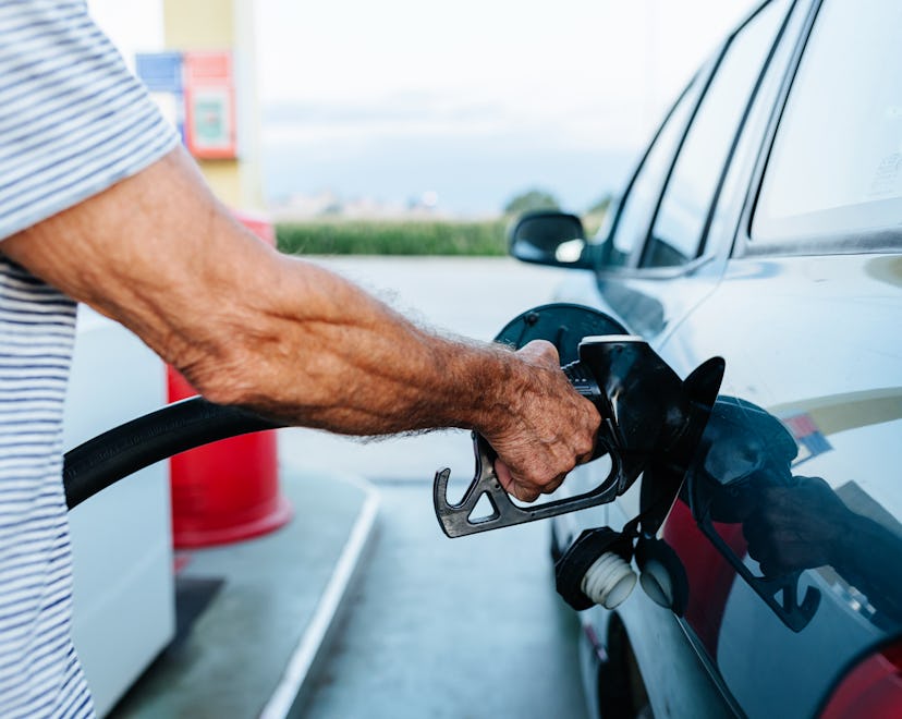 Close up view of a senior man filling the tank of his car at the gas station.