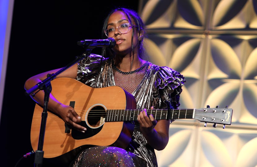 Folk singer Jensen McRae playing guitar and singing on stage.