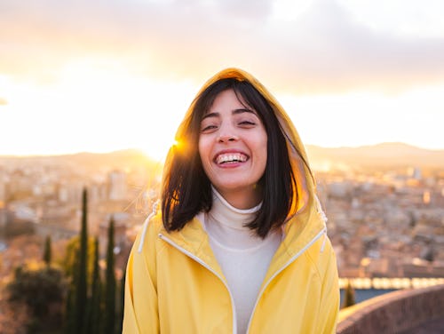 A woman smiles in front of a city scape. Here's how Aries season 2022 will affect each zodiac sign a...