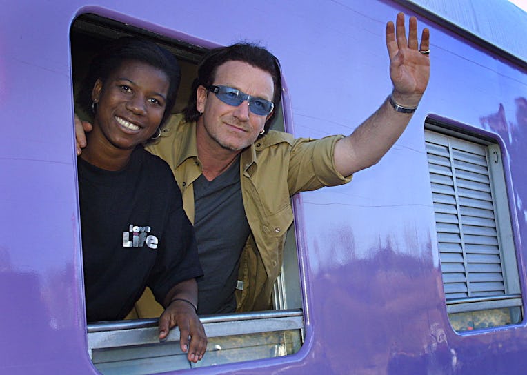 Irish rocker Bono, lead singer of U2 (R) and a Soweto schoolgirl, Melanie Chauke, wave from the Lo...