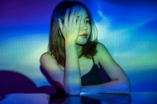 A woman covers her eye with her hand, bathed in blue light. Everything you need to know about Uranus...