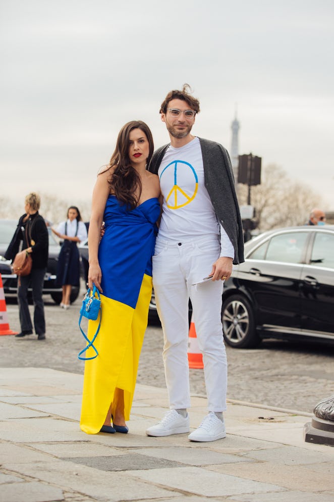 PARIS, FRANCE - MARCH 01: Two guests wear a blue and yellow Ukraine flag color dress (left) and a wh...