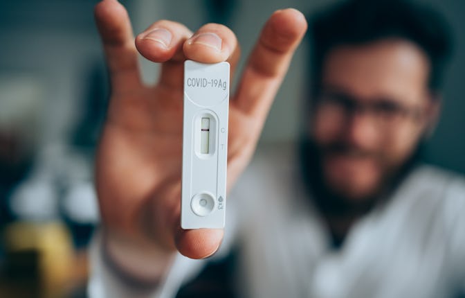 Close-up shot of man's hand holding a negative test device. Young man showing his negative Coronavir...