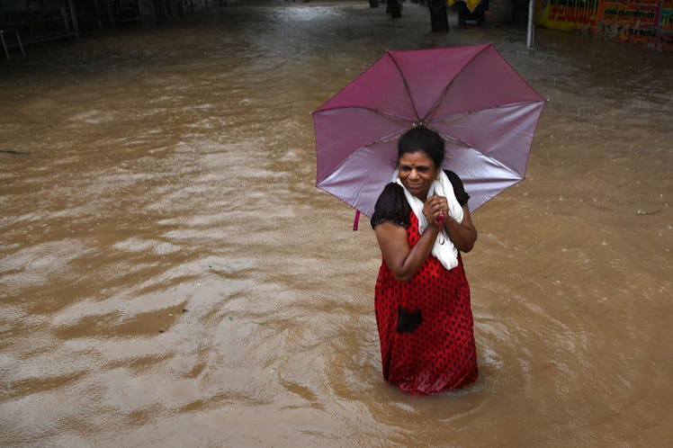 A woman wades along a waterlogged street during a heavy monsoon rainfall in Chennai on November 11, ...