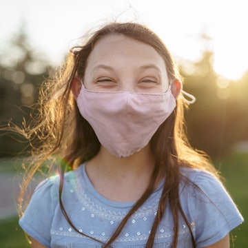A tween girl wearing a mask and smiling at the good news: a new study found that kids can have natur...