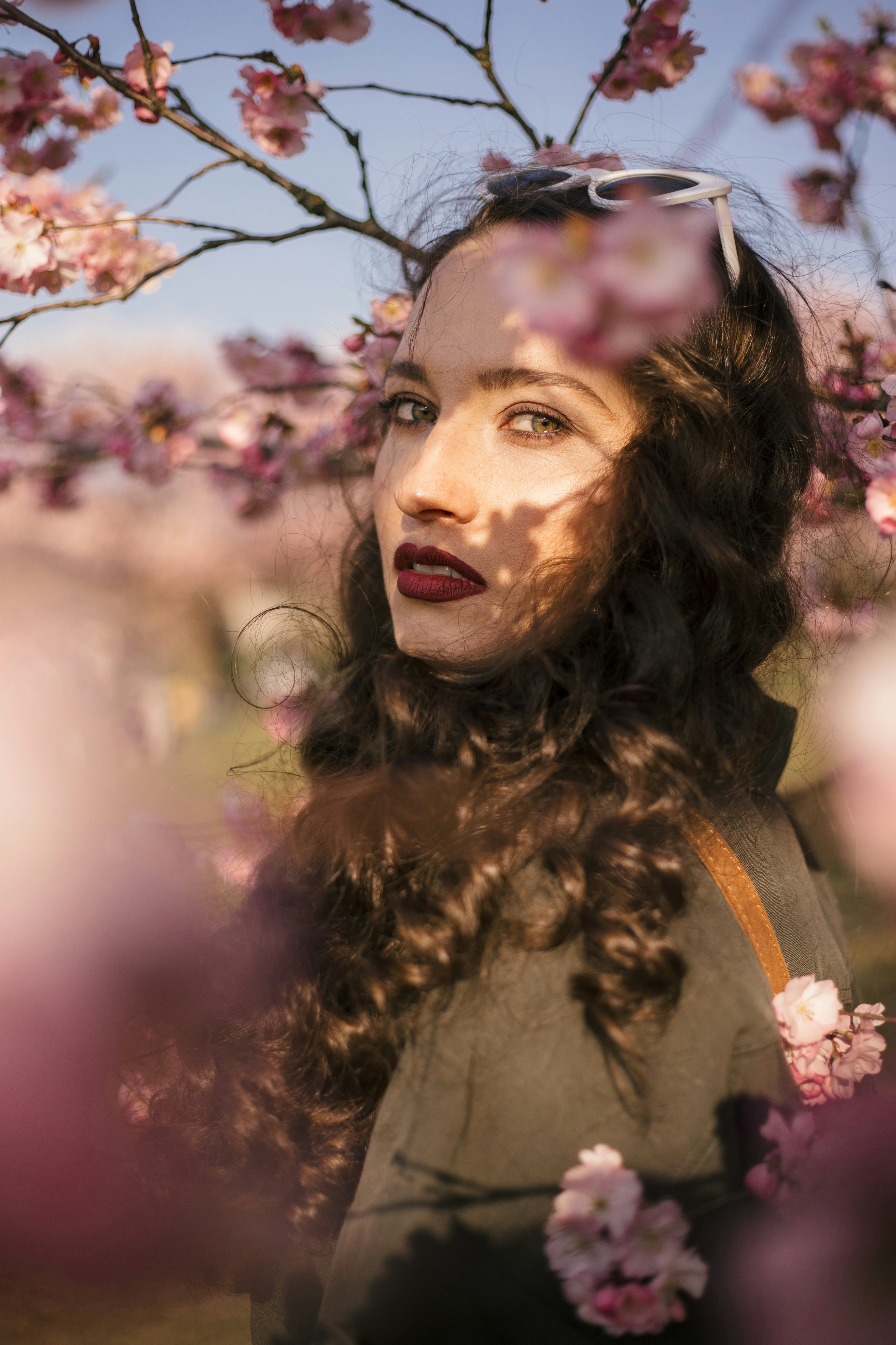 Young woman surrounded by flowers reflects on the 2022 pink moon, which will affect every zodiac sig...