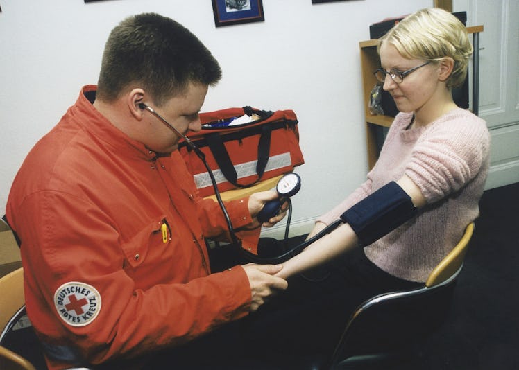 (GERMANY OUT) Ein Mitarbeiter des Deutschen Roten Kreuzes (DRK) misst mit einem Blutdruckmessgerät b...