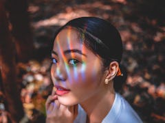 Woman wearing sunscreen under makeup looking into the sun with rainbows on her face