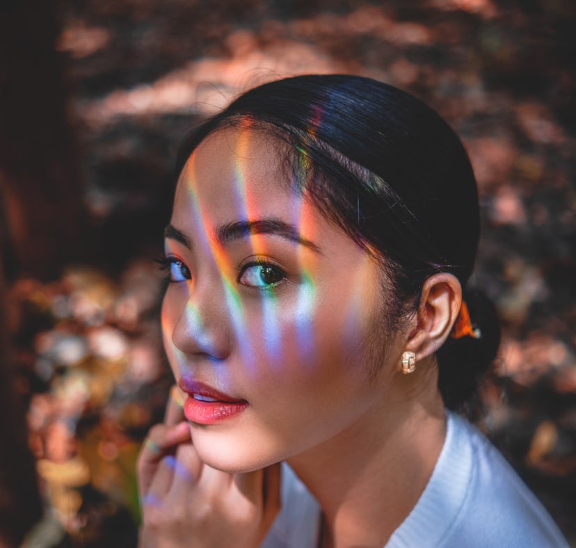 Woman wearing sunscreen under makeup looking into the sun with rainbows on her face