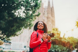 A woman takes photos while traveling. Here's your guide to aries season: aries season dates, aries s...