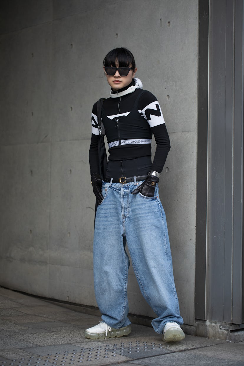 TOKYO, JAPAN - MARCH 16: A guest is seen wearing denim blue jeans, black and white sweater, black ny...