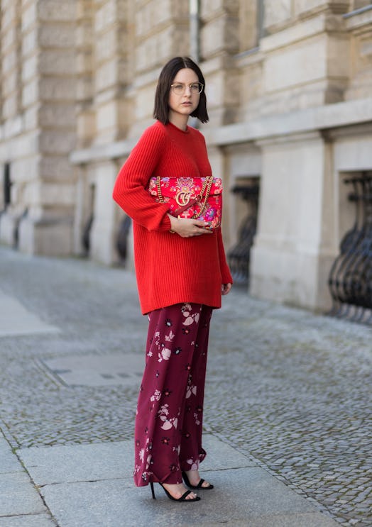 A model wearing red and a floral bag.