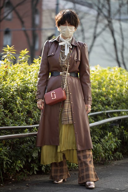 TOKYO, JAPAN - MARCH 16: A guest is seen wearing brown leather coat, plaid shirt, white scarf, pearl...