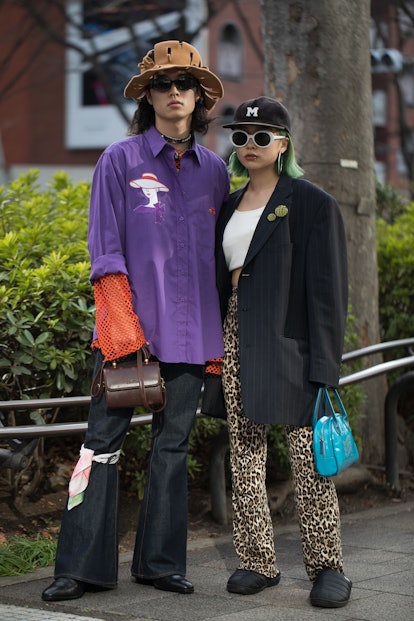 TOKYO, JAPAN - MARCH 16: Guests are seen wearing purple collared shirt, orange mesh shirt, brown bag...