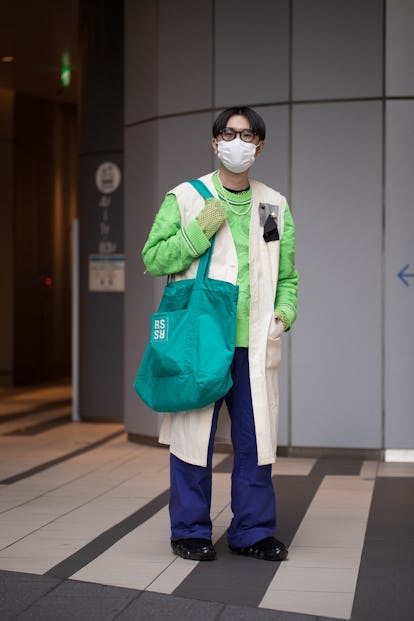 TOKYO, JAPAN - MARCH 15: A guest is seen wearing neon green sweater, white long vest, turquoise RS b...