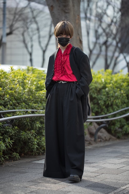 TOKYO, JAPAN - MARCH 16: A guest is seen wearing pink ruffled shirt, black jacket and pants outside ...