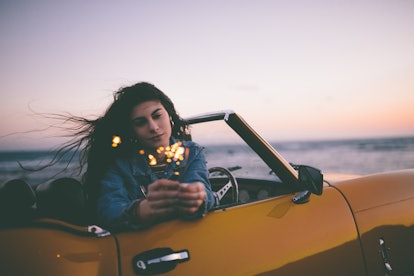 Young woman sitting in vintage car, knowing her unlucky zodiac sign will have the worst month of Apr...
