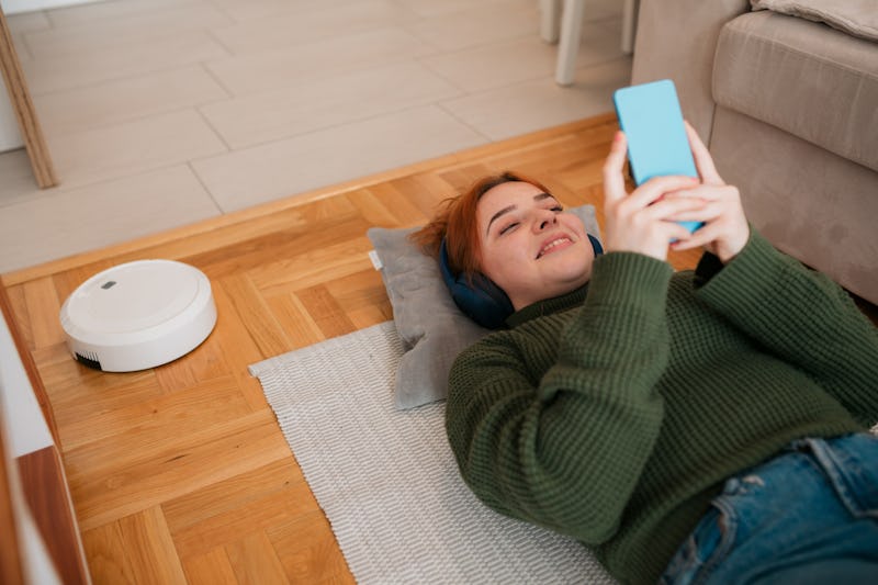 A woman lying on the floor sees who's liked your spotify playlist by going to a person's profile.