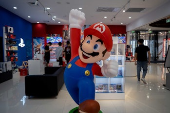 TIANJIN, CHINA - 2021/07/20: A cartoon figurine of Super Mario Bros. stands in front of a Nintendo S...