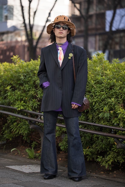 TOKYO, JAPAN - MARCH 15: A guest is seen wearing navy pinstripe suit, brown felt hat, purple shirt, ...